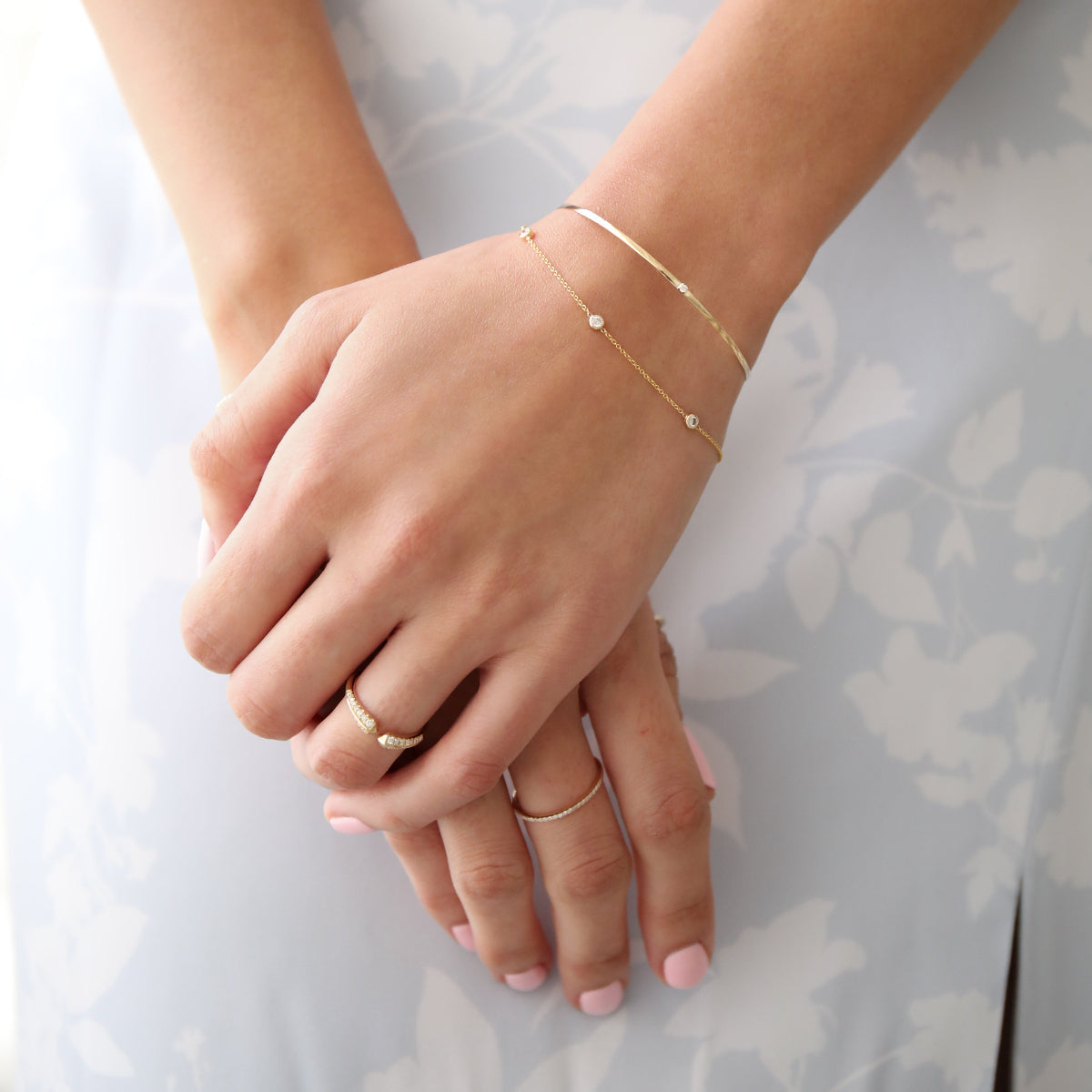 close up on a woman wearing 2 diamond bracelets and two diamond rings