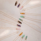 Assorted crystals pendants with diamonds arranged in an S shape on white fabric 