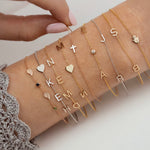 Collection of gold and silver bracelets with various charms on a person's wrist.