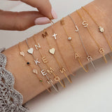 Collection of gold and silver bracelets with various charms on a person's wrist.