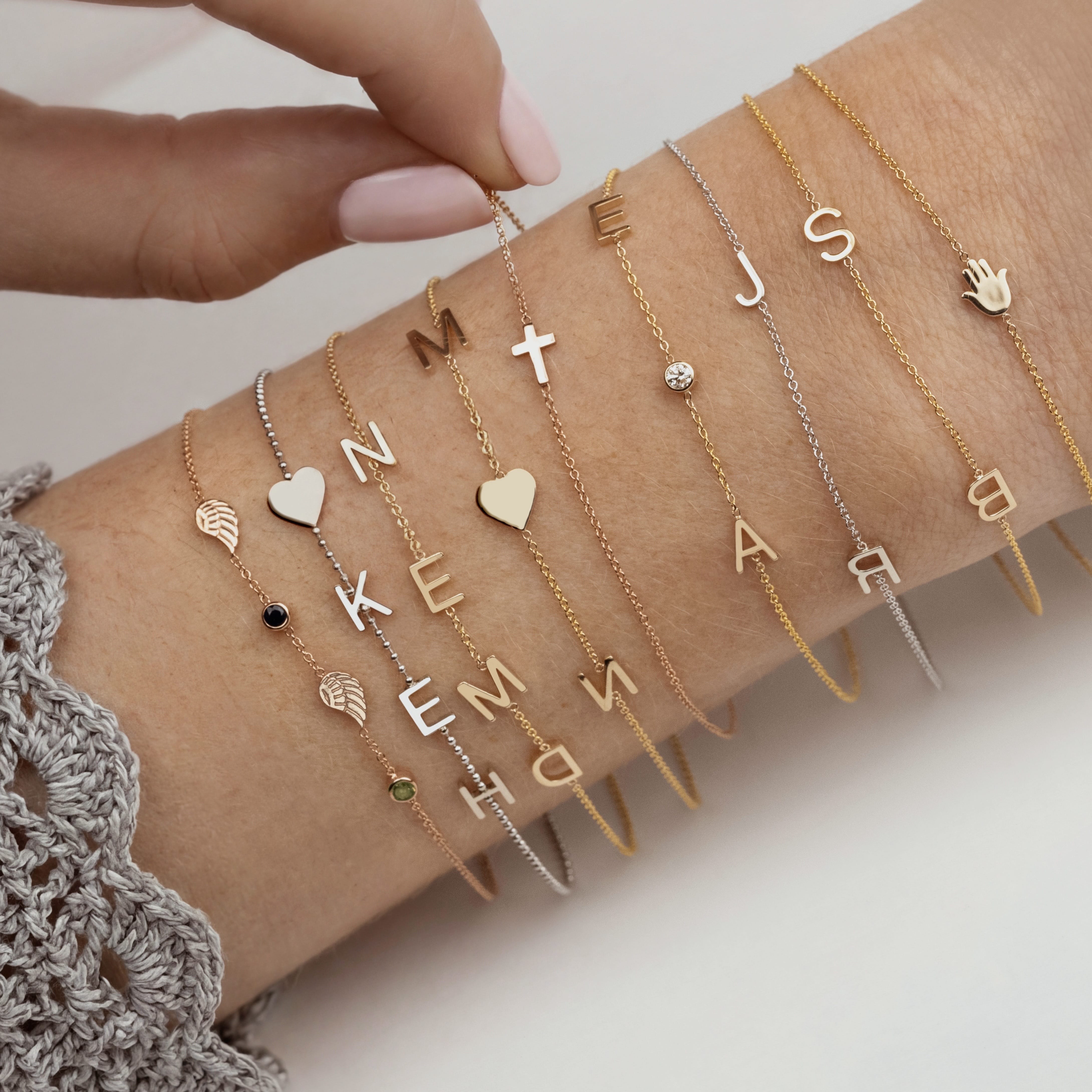 Collection of gold and silver bracelets with various charms on a person's wrist.