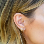 Close-up of an ear wearing a gold hoop earring with black accents.
