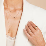 Gold jewelry including necklaces and rings on a person wearing a white garment.