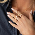 Close-up of a person wearing gold jewelry including a necklace, ring, and bracelet.