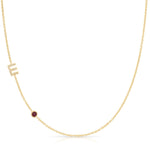 Gold necklace with a small red ruby on a white background