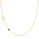 Gold necklace with a small red ruby on a white background