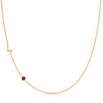 Gold necklace with a small ruby on a white background