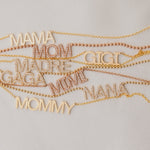 Gold necklaces with various mother wordplate necklaces on a light gray background