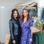 Abigail Spencer and Maya Brenner standing in front of a floral delivery truck in the background. 
