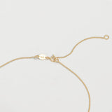 The back of a necklace in yellow gold on an off-white background. 