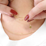 A close-up of the back of a neck wearing the Slide Chain and an Omega Chain, with hands featuring red nails holding the Slide Chain, in a white top.