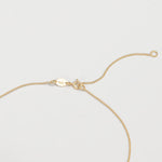 Gold necklace showing the adjustable jump ring on a light gray background