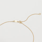 Gold necklace showing the adjustable jump ring on a light gray background