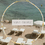 An Endless Summer Necklace - Saint-Tropez against a beach background with the text 'SAINT-TROPEZ' in the centre. 
