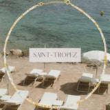 An Endless Summer Necklace - Saint-Tropez against a beach background with the text 'SAINT-TROPEZ' in the centre. 