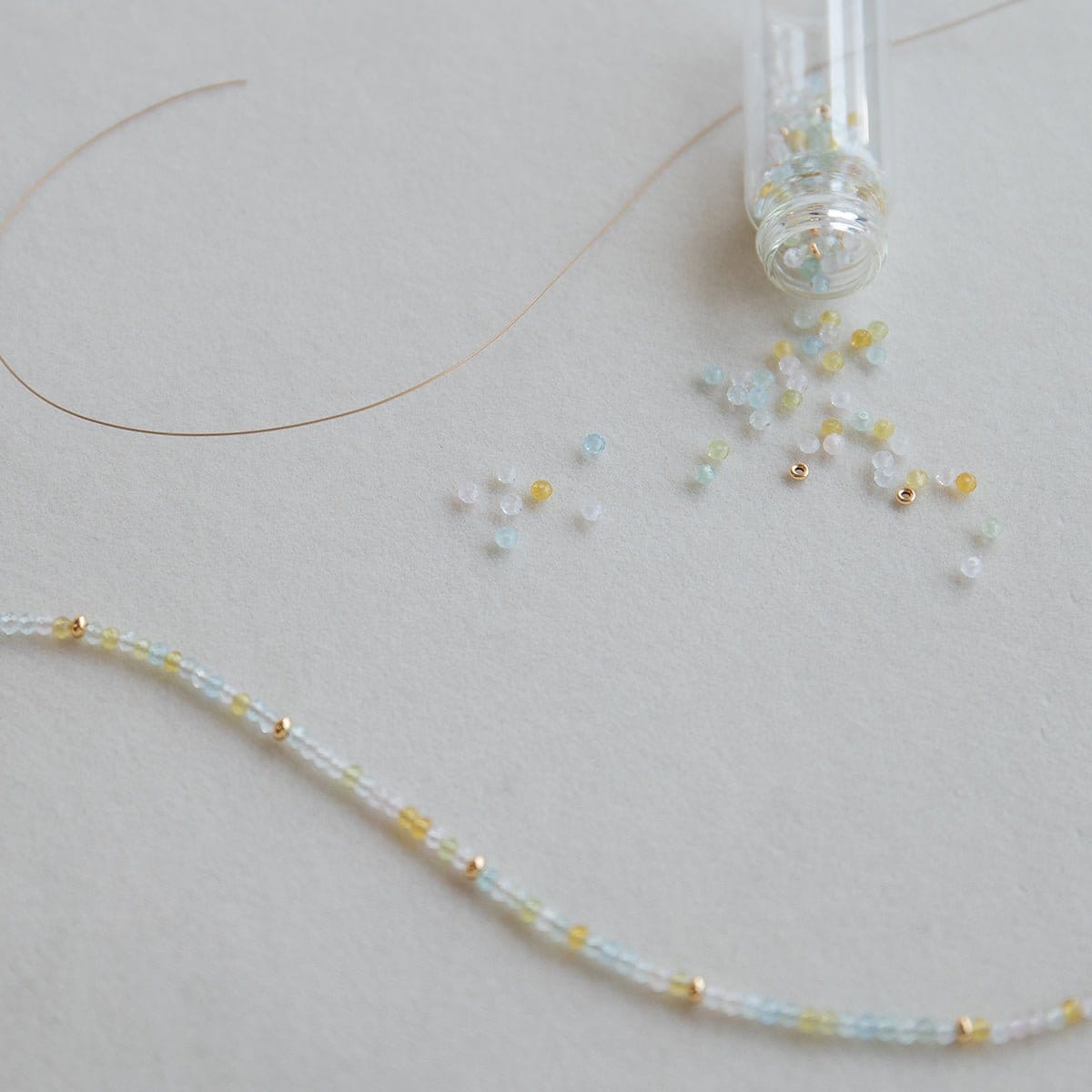 An Endless Summer Bracelet – Saint-Tropez laid out with a small clear container of beads on a light grey background.
