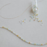 An Endless Summer Bracelet – Saint-Tropez laid out with a small clear container of beads on a light grey background.