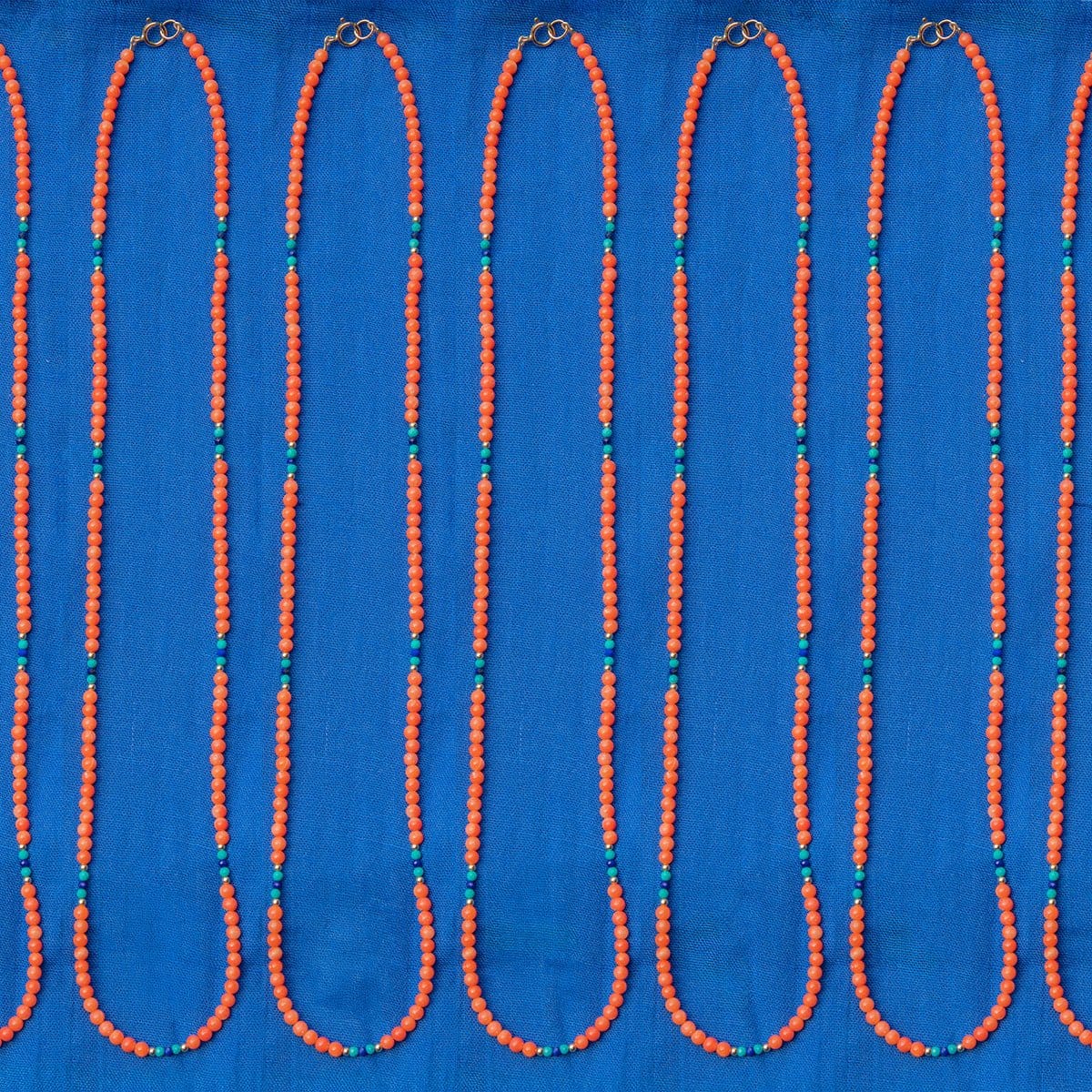 Several Endless Summer Necklaces - Calypso laid against a blue fabric background.
