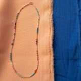 An Endless Summer Necklace - Capri against a blue and orange fabric background. 