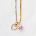 A Box Chain with a Cut Out Heart Charm and Color Pop Pendant in Light Pink (Pink Tourmaline) on a light grey background. 