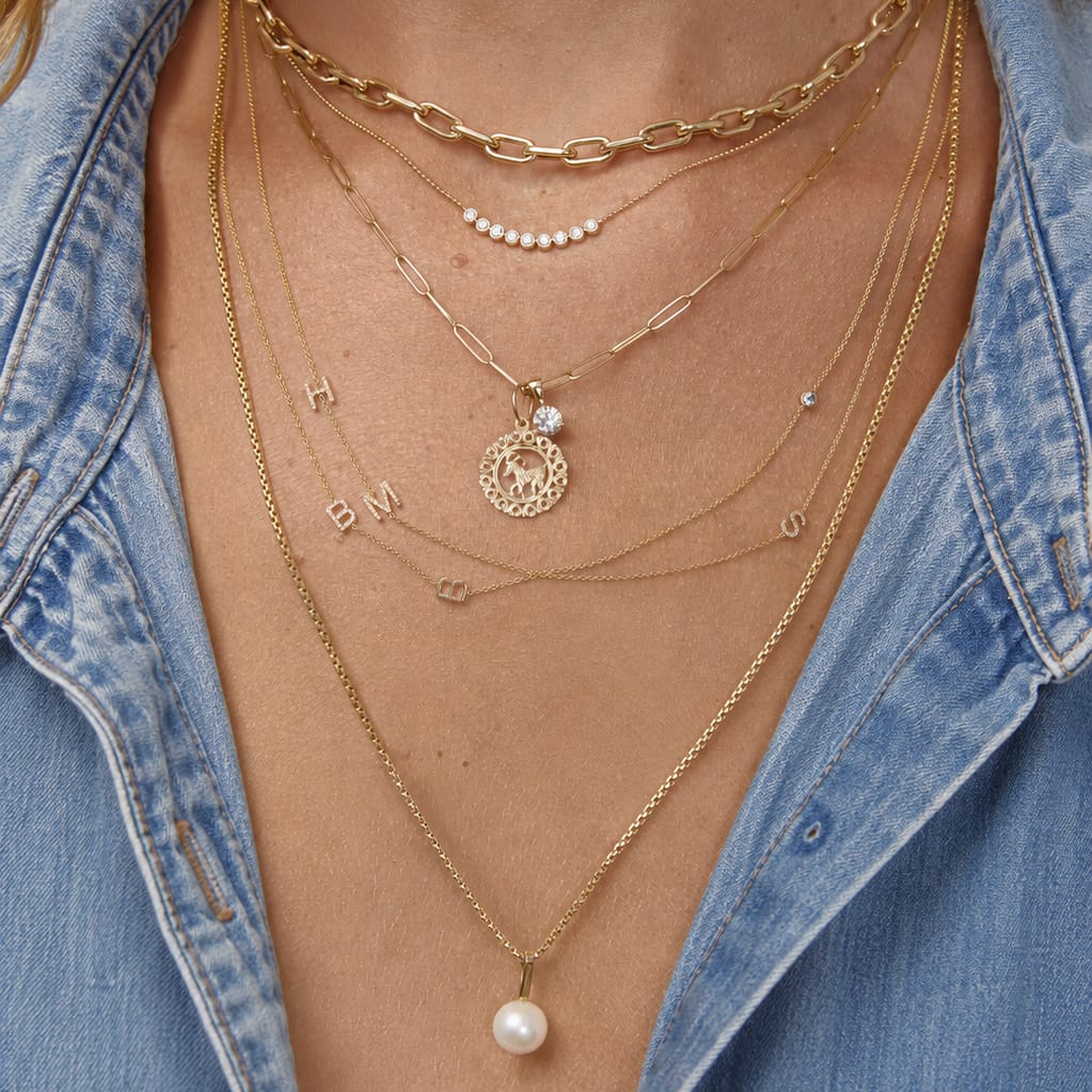 Close-up of layered gold necklaces with a denim shirt