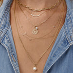 Close-up of layered gold necklaces with a denim shirt
