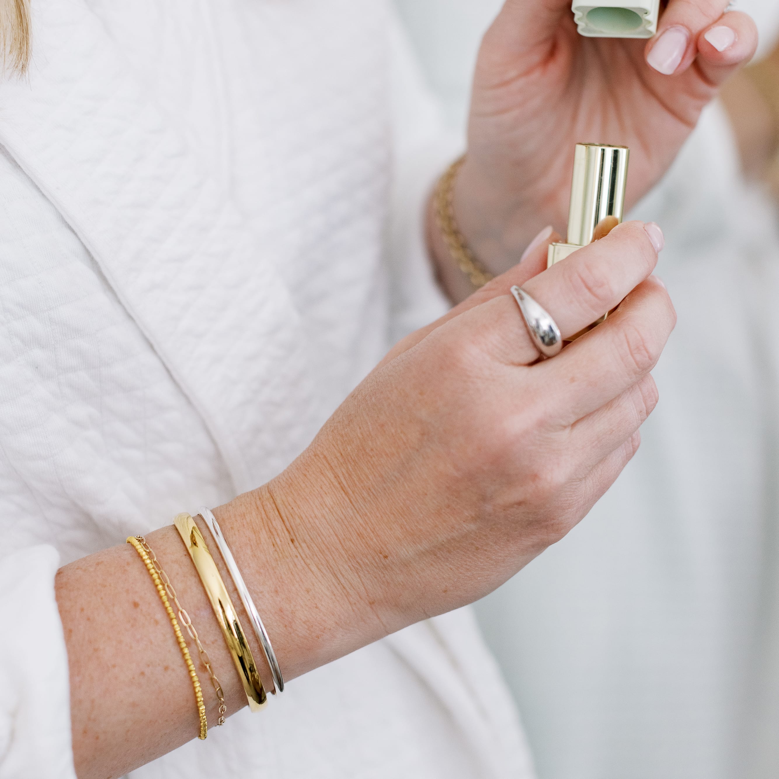Close-up of a hand holding a gold lipstick with a blurred background