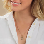 Close-up of a blonde woman wearing a Zodiac Necklace - Cancer with a white shirt against a neutral background. 