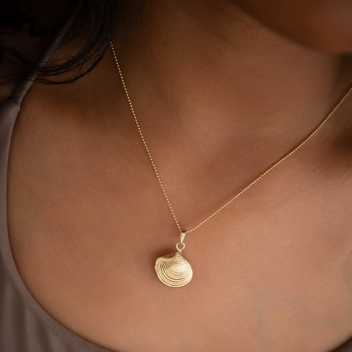 Close-up of a neck wearing a Classic Bead Chain with a Golden Coast Shell. 