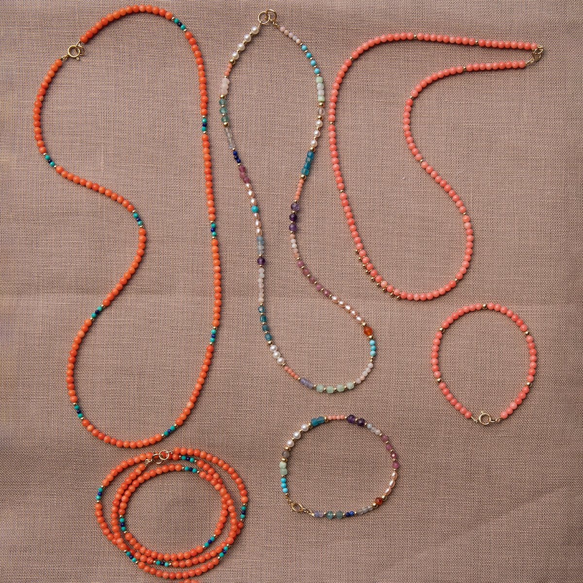 Endless Summer Bracelets and Necklaces in Mykonos, Calypso and Capri) on a beige fabric background. 