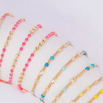 Several Confetti Necklaces in pink, blue and yellow on a white background. 