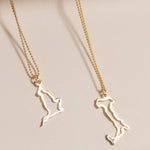 An England Necklace and an Italy Necklace laid on a cream surface against a light brown background.