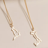 An England Necklace and an Italy Necklace laid on a cream surface against a light brown background.