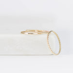 Delicate Trio Stacking Rings in yellow gold on a white surface and background. 