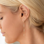Close-up of a Stardust Earring in yellow gold shown on a blonde woman's ear. 