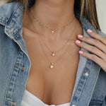 A decellotage wearing a Duchess Diamond Pendant on The Slide Chain, Princess Diamond Pendant on a Short Element Link Chain and a Queen Diamond Pendant on a Classic Bead Chain with a white top and denim jacket. 