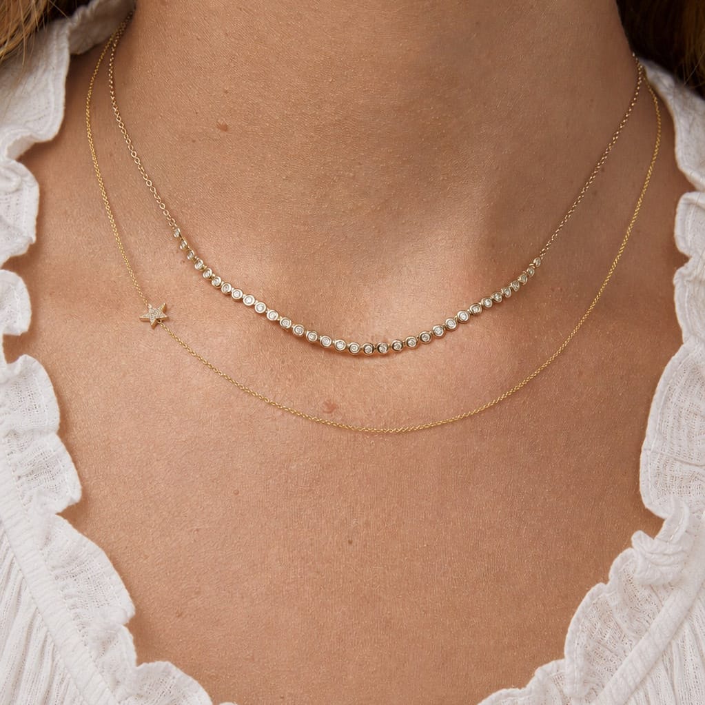 Close-up of a person wearing two gold necklaces with a white lace garment.