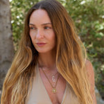 Woman with long blonde hair wearing layered necklaces outdoors