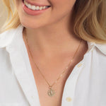 Close-up of a blonde woman wearing a Zodiac Necklace - Gemini with a white shirt against a neutral background. 