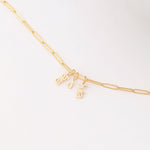 An Element Long Link Chain with three Petite Nameplate Pendants, 'lara', 'd' and 'livia', all in yellow gold on a white background. 