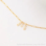 An Element Long Link Chain with three Petite Nameplate Pendants, 'lara', 'd' and 'livia', all in yellow gold on a white background. 