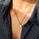 14k gold MUM word plate necklace with heart locket pendant worn on model.