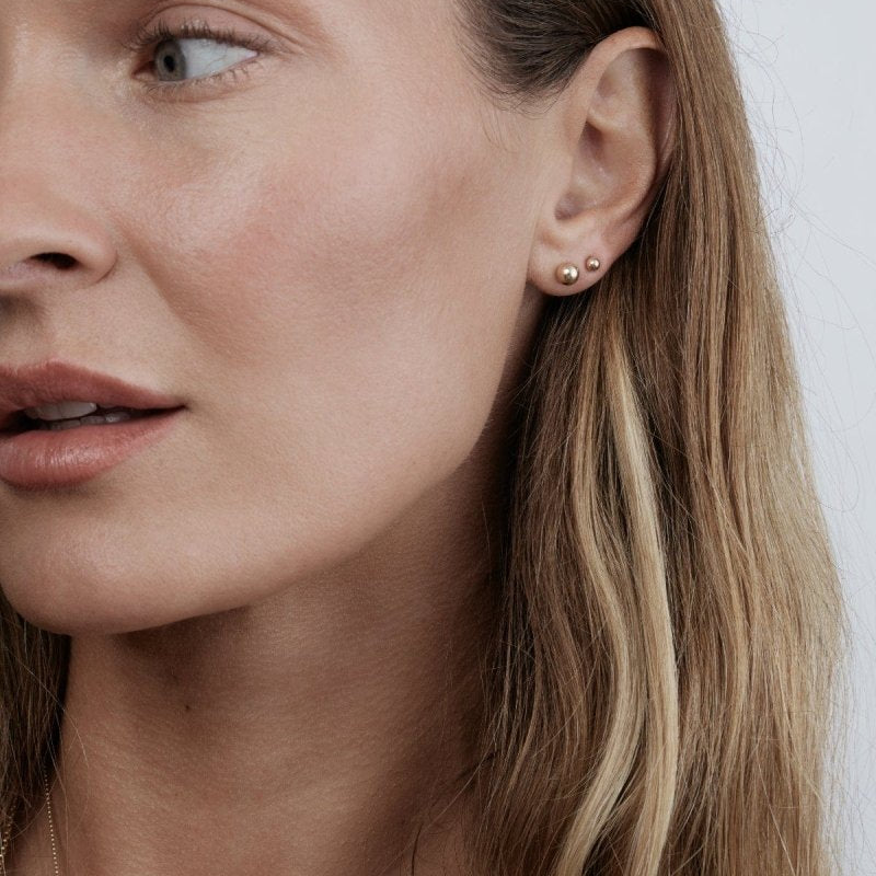 Close up of woman wearing gold post studs