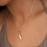 Close-up of a neck wearing a Golden Spiral Shell on The Slide Chain with a light brown strap top. 