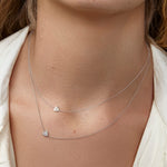Close-up of a person wearing two silver heart-shaped pendant necklaces.