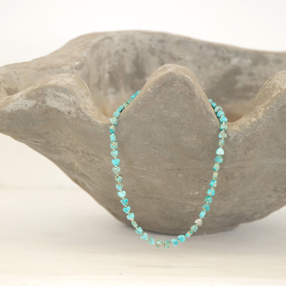 An Endless Summer Necklace - Sea + Sky laid on a textured stone bowl against a white background. 