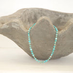 An Endless Summer Necklace - Sea + Sky laid on a textured stone bowl against a white background. 