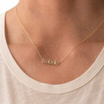 Gold 'Isabella' necklace on a person wearing a beige top