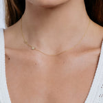 Gold necklace with a small pendant on a person's neck