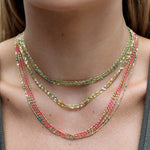 Close-up of a neck wearing multiple Confetti Necklaces in green, blue, pink and yellow. 